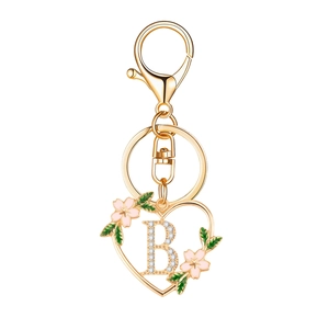 Golden heart-shaped keychain with crystal letter B and pink cherry blossoms on white