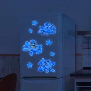 Close-up of glowing blue cartoon animal airplane wall stickers on a fridge in the dark