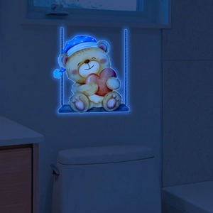 Glow-in-the-dark bear on a swing wall sticker showing blue neon light in a dark room