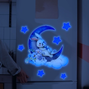 Luminous cartoon rabbit on moon wall decal glowing bright blue in a dark room setting