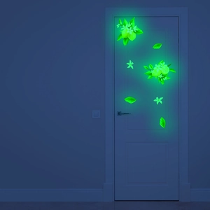 Luminous lemon and flower stickers glowing on a white door in a dark room environment