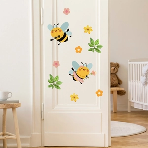 Detailed view of luminous bee and flower wall decals on a white nursery door