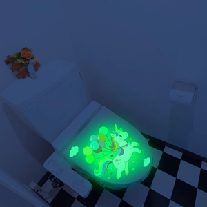 Luminous unicorn wall sticker with balloons glowing green in a dark bathroom setting