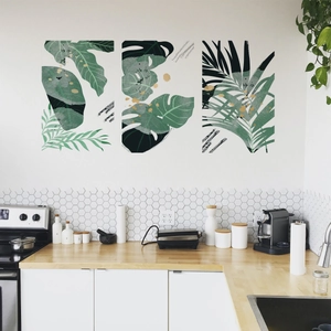 Set of three tropical monstera and palm leaf wall art prints with gold accents in kitchen