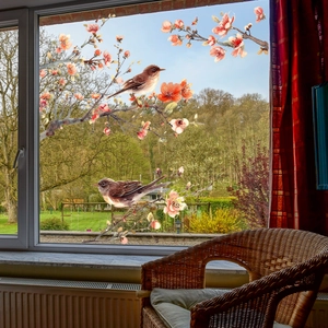 Detailed view of floral glass window clings with birds and pink blossoms on glass