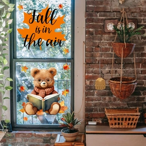 Window static cling featuring a bear reading a book and 'Fall is in the air' maple leaf