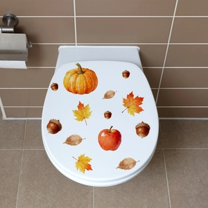 Close-up of autumn pumpkin and maple leaf stickers on a white toilet lid cover