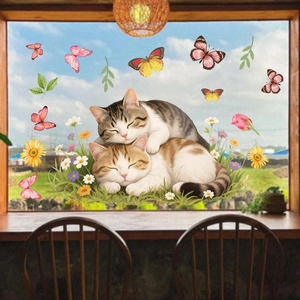 Detailed view of cat and butterfly static window clings on a glass surface with floral garden backdrop