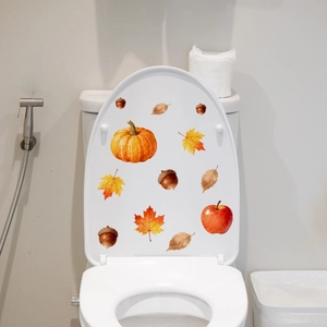 Watercolor pumpkin and autumn leaves stickers applied on a white toilet lid cover