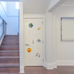 Luminous outer space wall stickers with watercolor planets and UFO on a white bedroom door