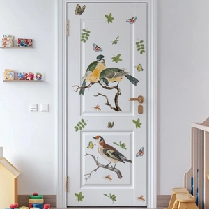 Detail of adhesive wall stickers with birds, butterflies and green leaves on a white door