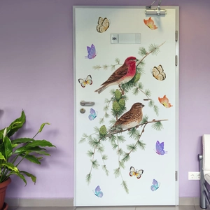 Detail of realistic bird and butterfly wall stickers on a white door with pine branches