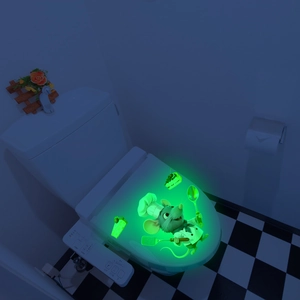 Glow-in-the-dark 3D chef mouse wall decal glowing on a toilet lid in a dark bathroom