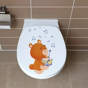 Detailed view of luminous cartoon bear playing drums sticker on a white toilet lid cover