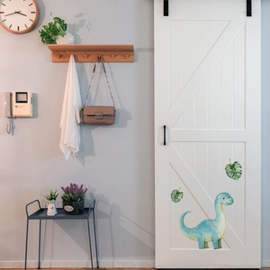 Detailed view of watercolor glow-in-the-dark dinosaur and monstera leaf wall stickers on a door