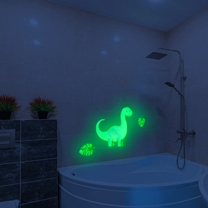 Luminous green cartoon dinosaur and leaves wall sticker glowing in a dark bathroom setting