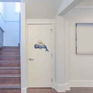 Watercolor whale and sailboat wall sticker with stars applied on a white interior door