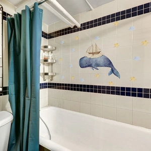 Deep blue watercolor whale wall sticker with yellow stars applied on bathroom tiles