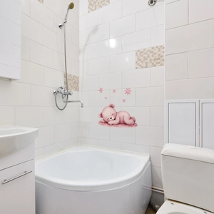 Detailed view of a cute sleeping pink bear and stars wall sticker on white bathroom tiles