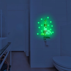 Luminous wall sticker showing a green glowing lighthouse and waves in a dark bathroom