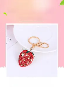 Detailed view of red rhinestone strawberry keychain with green leaves and gold metal ring