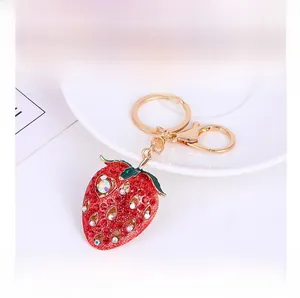 Detailed macro view of strawberry keychain with red crystals and golden lobster clasp closure