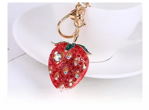 Detail view of a strawberry keychain with red rhinestones and golden metal lobster clasp