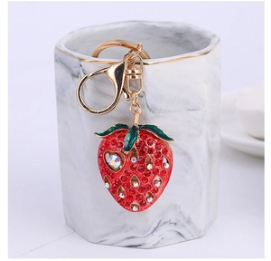 Detailed view of strawberry keychain with red rhinestones on marble mug rim