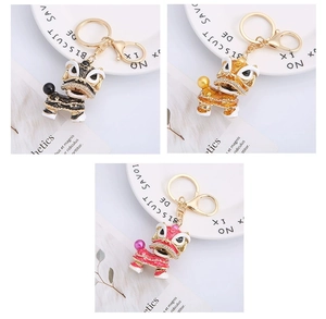 Three Chinese lion dance keychains in black, orange and pink with rhinestones