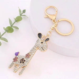 Gros plan d'un porte-clés girafe doré orné de strass brillants violets et blancs