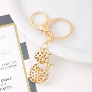 Creative gold cat keychain with rhinestone heart and cut-out pattern on white ceramic