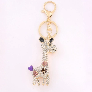 Porte-clés girafe doré orné de cristaux avec pendentif cœur violet sur fond blanc