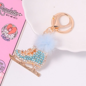 Vue détaillée du porte-clés patin à glace avec strass bleus et pompon en fourrure douce