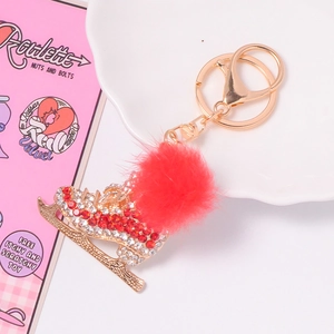 Détail d'un porte-clés patin à glace doré avec strass et pompon en fourrure rouge