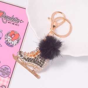 Détail du porte-clés patin à glace doré avec strass et pompon en fausse fourrure noire