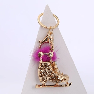 Détail du porte-clés patin à glace doré avec pompon violet et motifs de cœur évidés