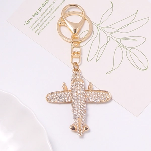 Detailed close-up of a sparkling gold airplane keychain with rhinestones on a stylish card