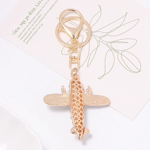Golden vintage airplane model keychain with intricate hollow patterns on wings
