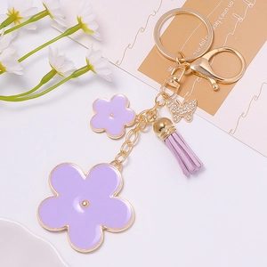 Detailed close-up of purple flower keychain with butterfly pendant and leather tassel