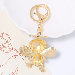 Porte-clés abeille en métal doré avec fermoir mousqueton sur fond décoratif