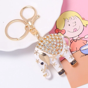 Detailed macro view of white enamel elephant keychain with sparkling rhinestones and gold flowers