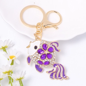 Détail d'un porte-clés poisson doré avec des pierres précieuses mauves et des cristaux