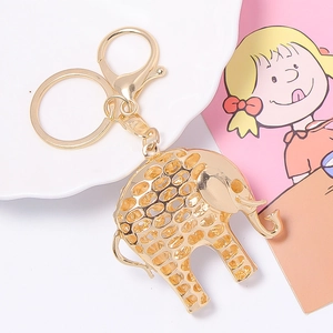 Elegant gold hollow elephant keychain with lobster clasp on a decorative white dish