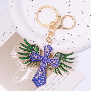 Detailed macro view of golden metal cross keychain with blue enamel and rhinestone wings