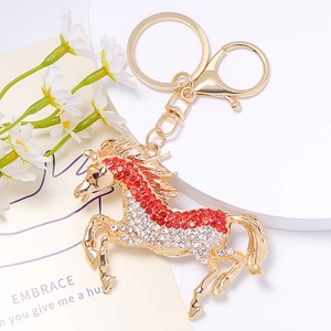 Détail du porte-clés cheval orné de strass rouges et blancs étincelants sur métal doré