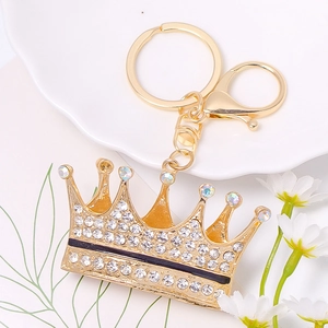 Detail of a gold crown keychain with sparkling rhinestones on a white ceramic tray