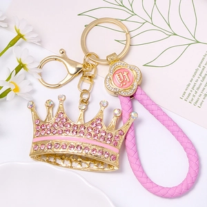 Close-up of pink rhinestone crown keychain with gold plating and leather braided cord