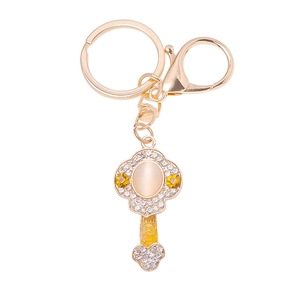 Close-up of golden Ruyi keychain with yellow cat-eye stone and crystal rhinestones