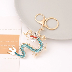Golden dragon keychain with sparkling light blue and white rhinestones on white background