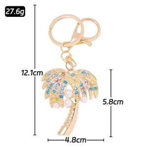 Golden coconut tree keychain with colorful rhinestones and white pearls on white background